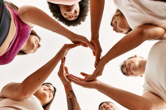 Group of young friends doing circle symbol with hands together